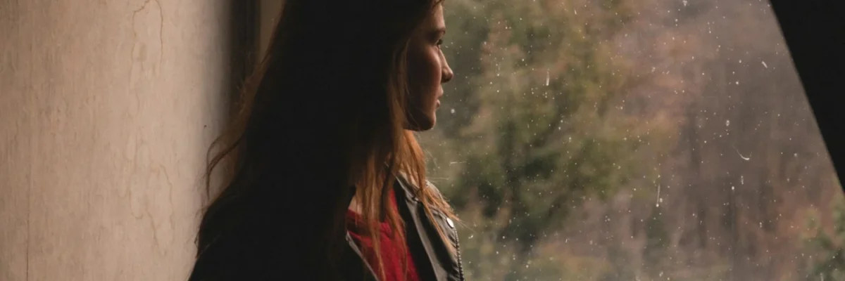 a woman standing in front of a window looking out